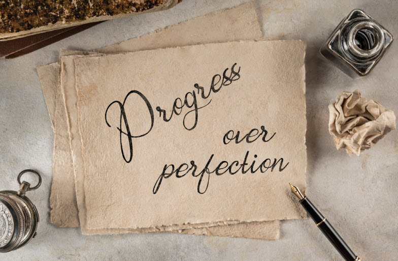 A vintage-style paper with the words 'Progress over perfection' written in elegant script, surrounded by an ink bottle and pen' and embrace the 1% principle for epic personal growth.