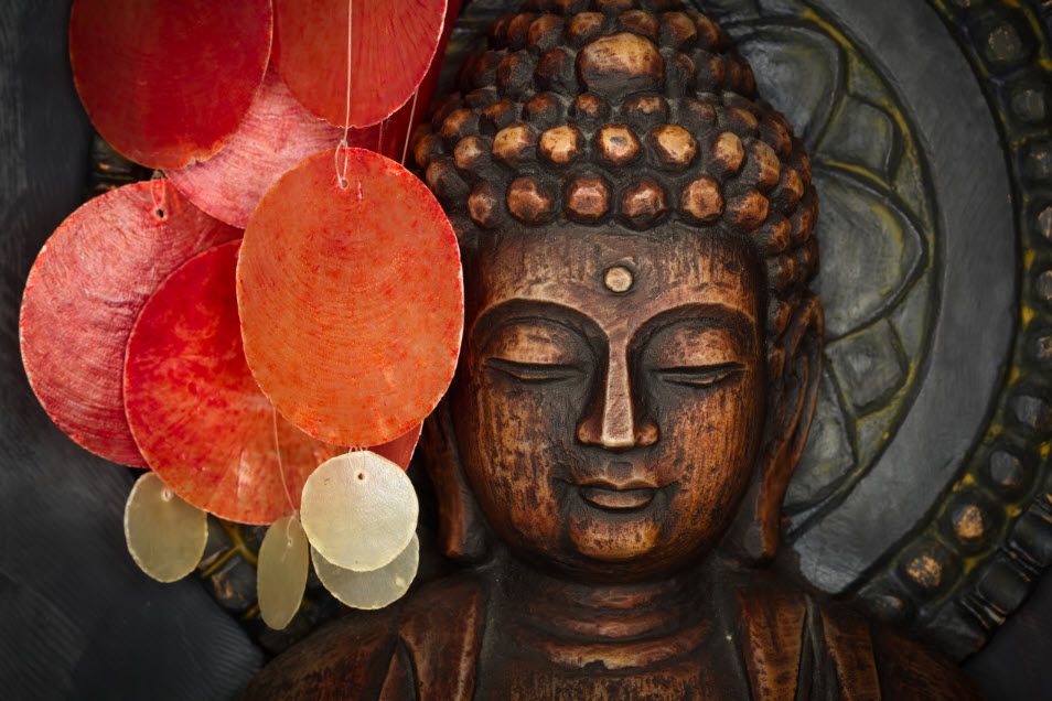 A copper headshot of the Buddhist icon with a contrasting colorful hanging shell mobile depicting the modern and ancient.