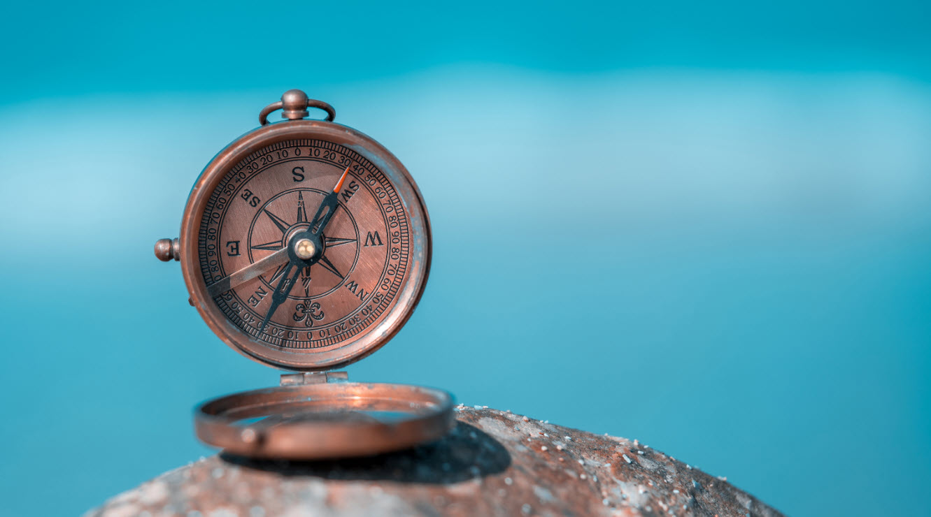 A compass sits atop what appears to be a rock. It depicts the inner compass working in us.