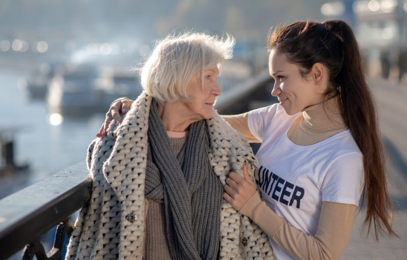 A young woman shows kindness towards an elderly woman on a walk.