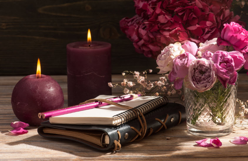A tranquil setting with flowers and candles. A journal lay waiting. Mindfulness isn’t just a mental exercise, it’s deeply connected to our body’s well-being and mental wellness.