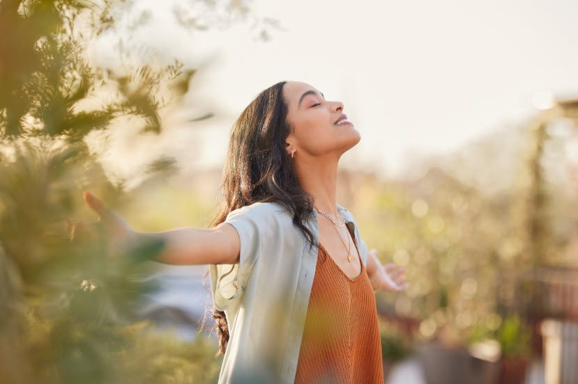 A woman has her arms outstretched in a natural environment as she embraces her true self on her journey to reconnect with her spirit.
