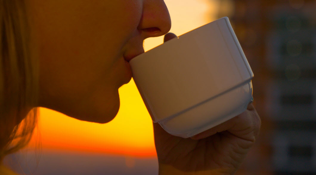 A woman is sipping a cup of tea as the sun rise. Taking life from performative to personal is powerful. You need presence and awareness for a few minutes to connect to yourself and others.