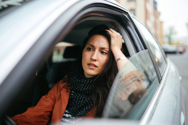 A woman sitting in her car looking pensive. She appears to be rethinking her purpose because something is missing.